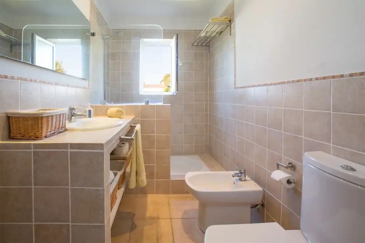 A tiled bathroom with a sink, bidet, and toilet.