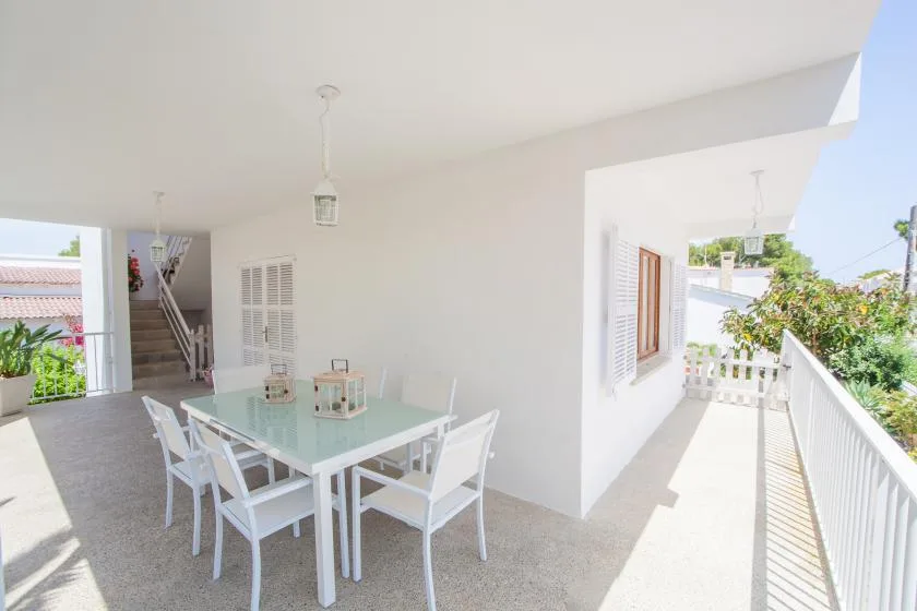 A bright dining area with a glass table opens onto a sunny balcony.