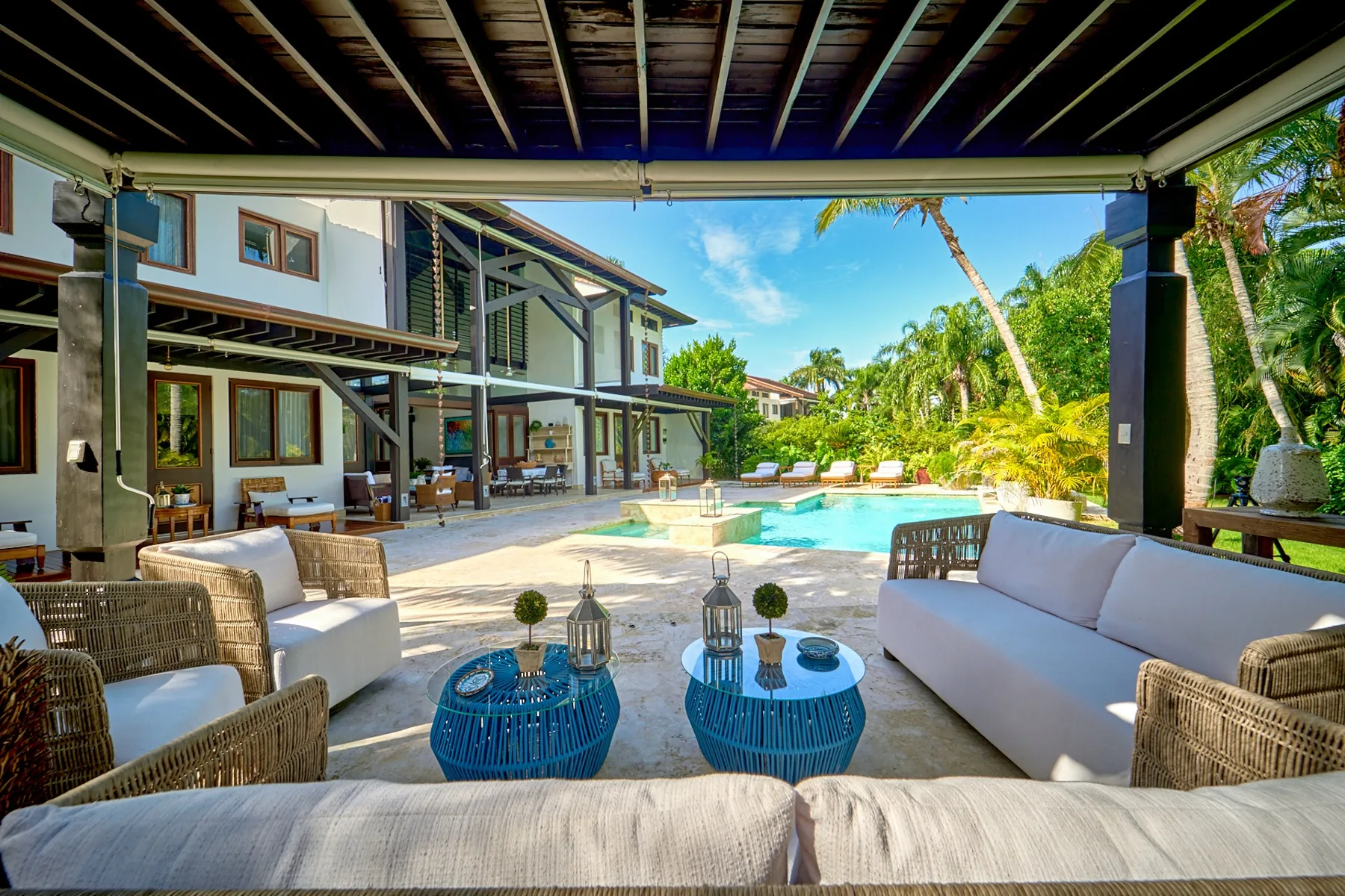 A covered outdoor seating area overlooks a swimming pool and tropical garden.