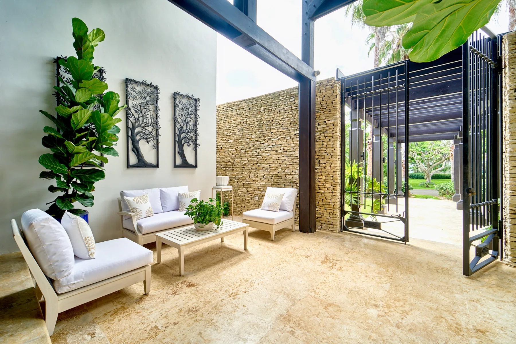 An outdoor seating area with pale furniture and an open black gate.