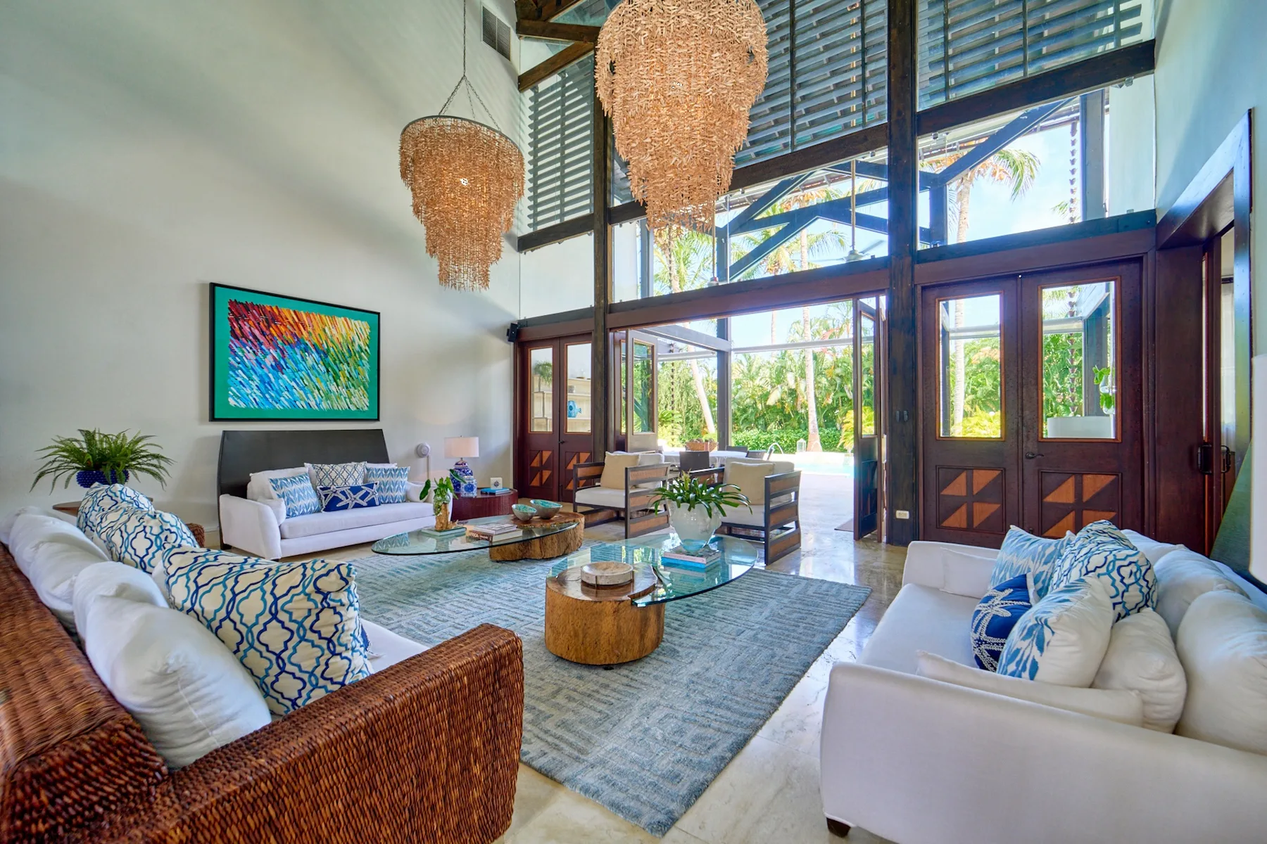 A bright living room with seating around a glass coffee table and large windows.