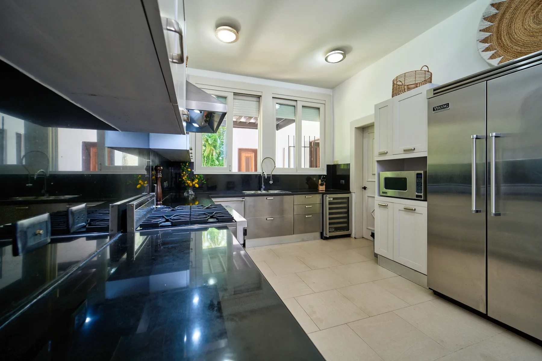 A modern kitchen with dark countertops, stainless steel appliances, and a central work surface.