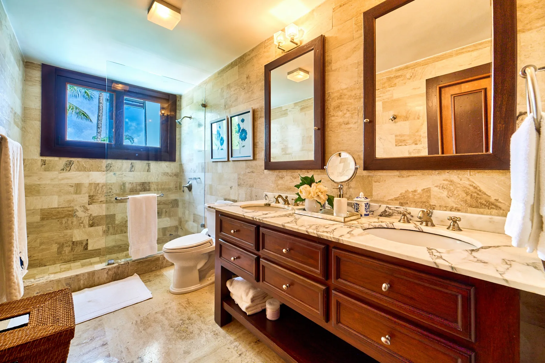 A bathroom with a long vanity, wall mirrors, and a glass shower.