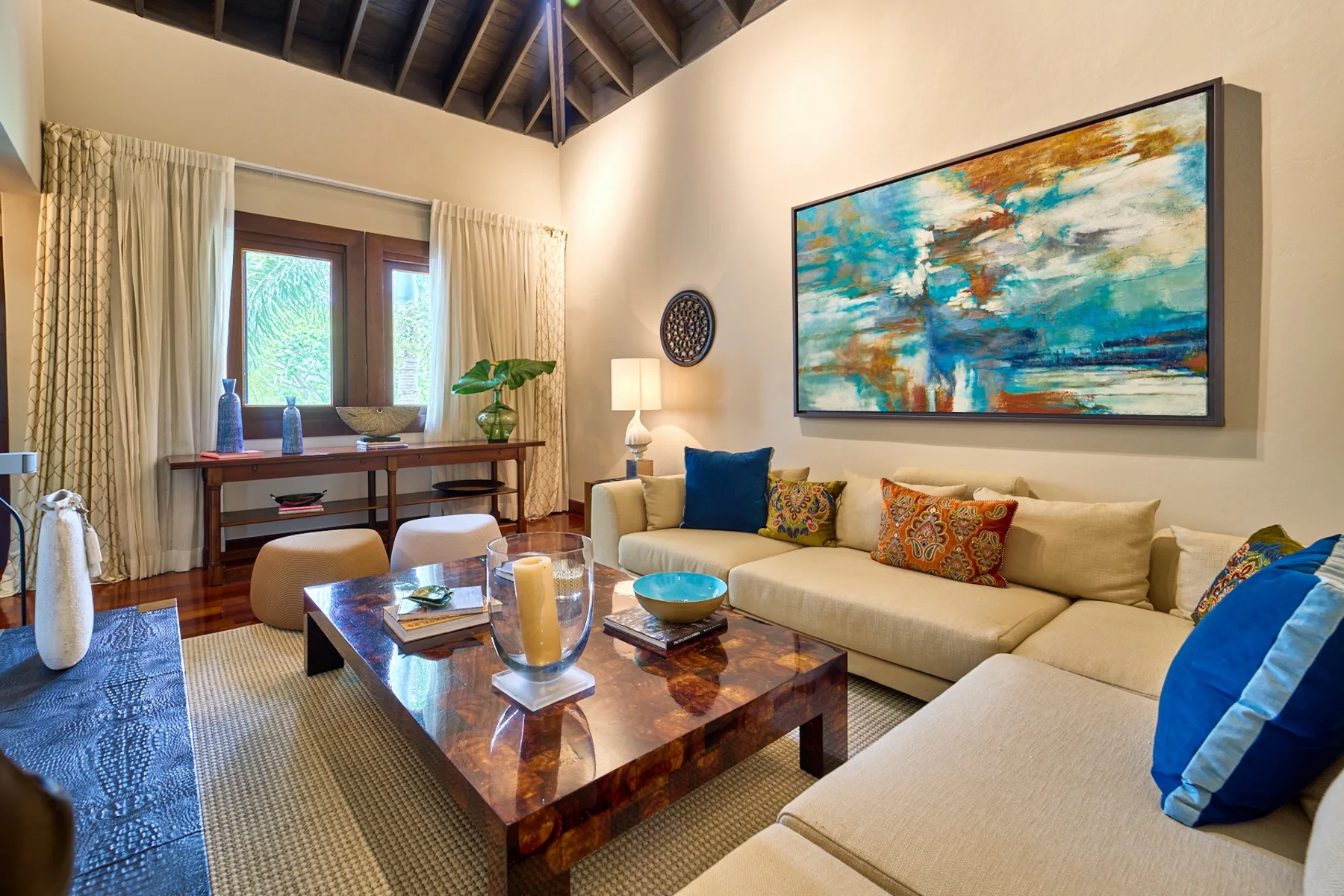 A living room with an L-shaped seating area and a large abstract painting.