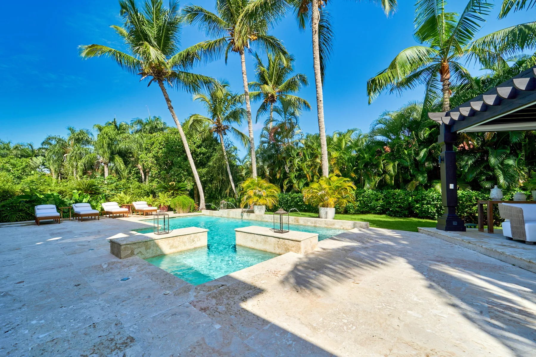 A swimming pool surrounded by palm trees and a paved patio.