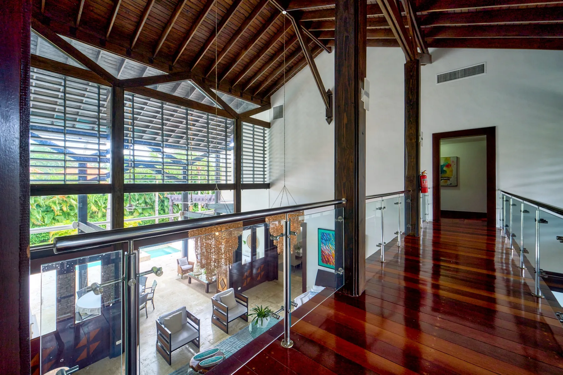 A bright interior walkway overlooks a lower seating area through large windows.