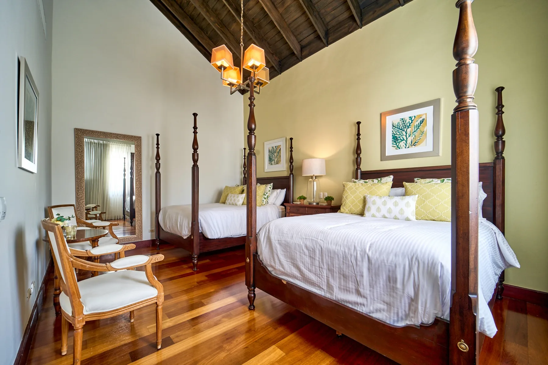 A bedroom with two beds, wooden seating, and a sloped timber ceiling.