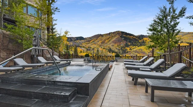 Una terraza con piscina y tumbonas al aire libre ofrece vistas a colinas boscosas.