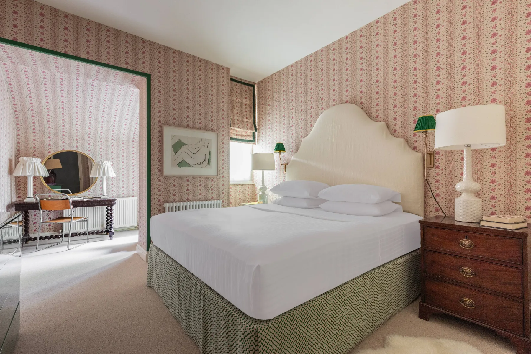 Un dormitorio con una cama grande, papel tapiz estampado y muebles de madera junto a la cama.