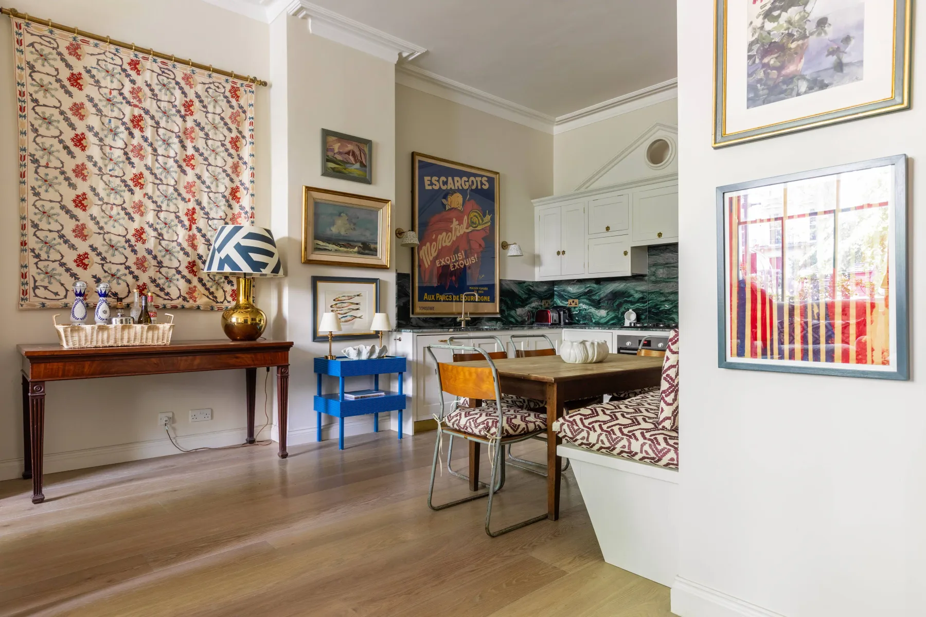 Comedor con una mesa de madera, asientos estampados y una cocina compacta.