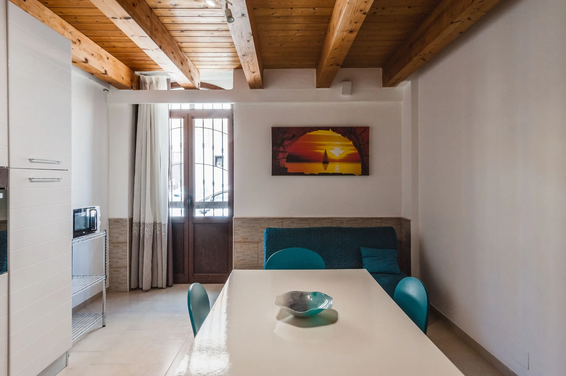 Comedor con una mesa y asientos bajo vigas de madera vistas en el techo.