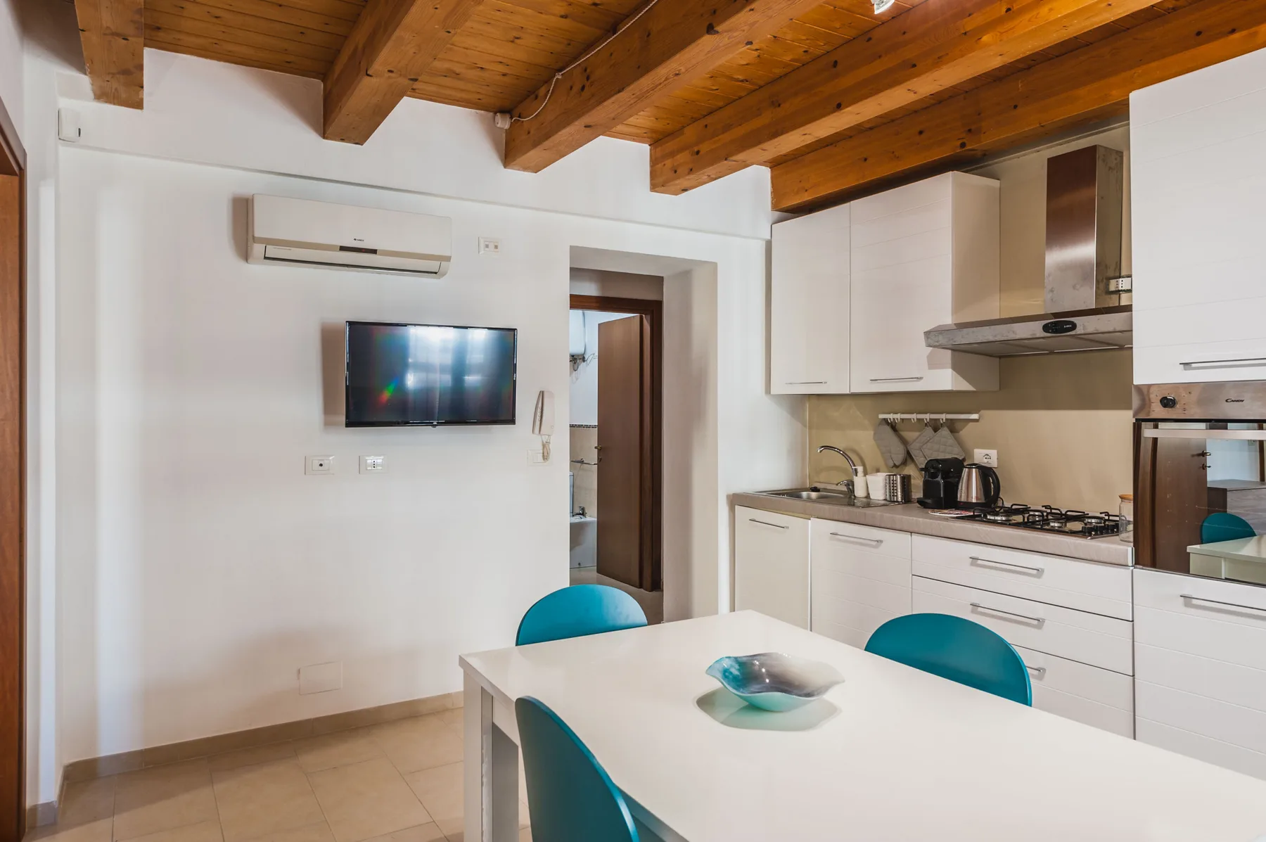 Un comedor con una mesa blanca junto a una cocina equipada.