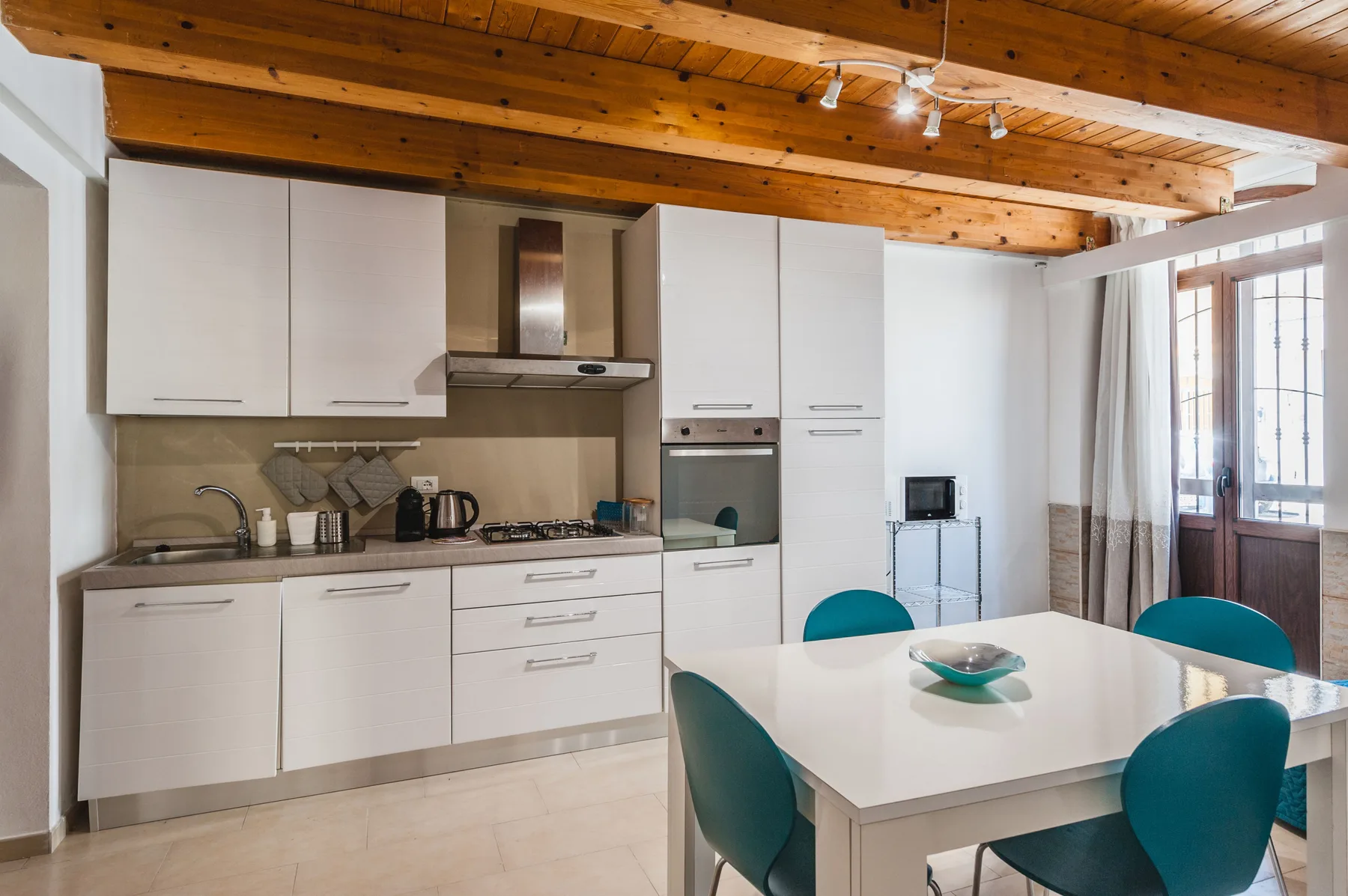 Una cocina y comedor luminosos con armarios blancos y una mesa.