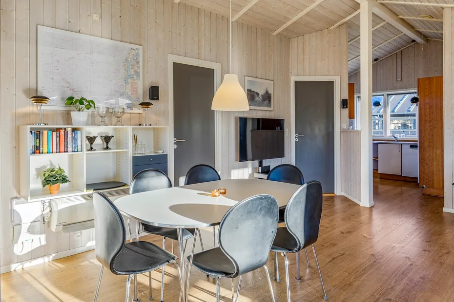 Comedor con una mesa y sillas junto a un televisor montado en la pared.