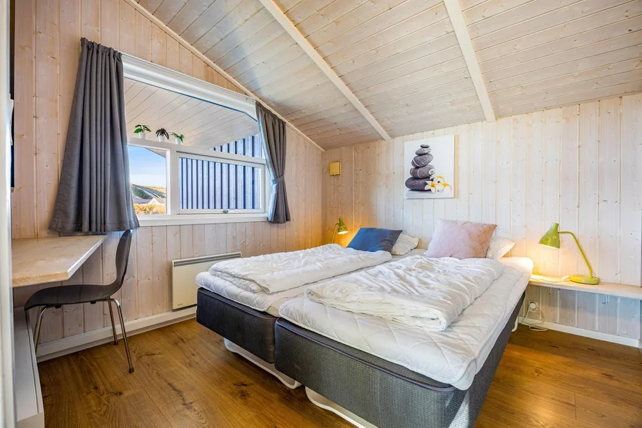 Un dormitorio con una cama bajo un techo inclinado de madera clara.