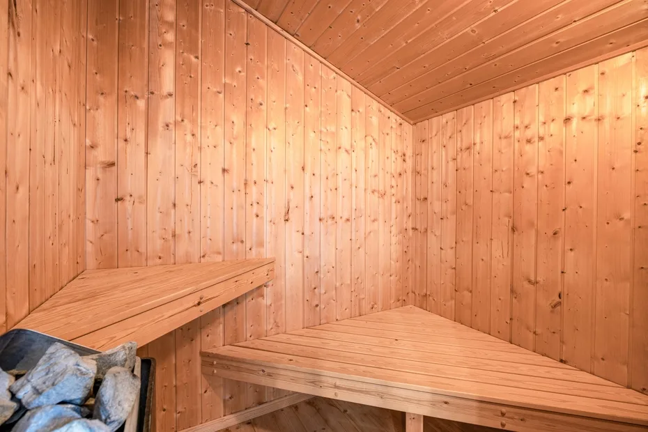Una sauna revestida de madera con bancos y una cesta de piedras.