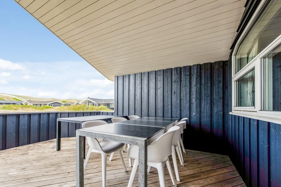 Comedor exterior cubierto con una mesa y sillas junto a una ventana.