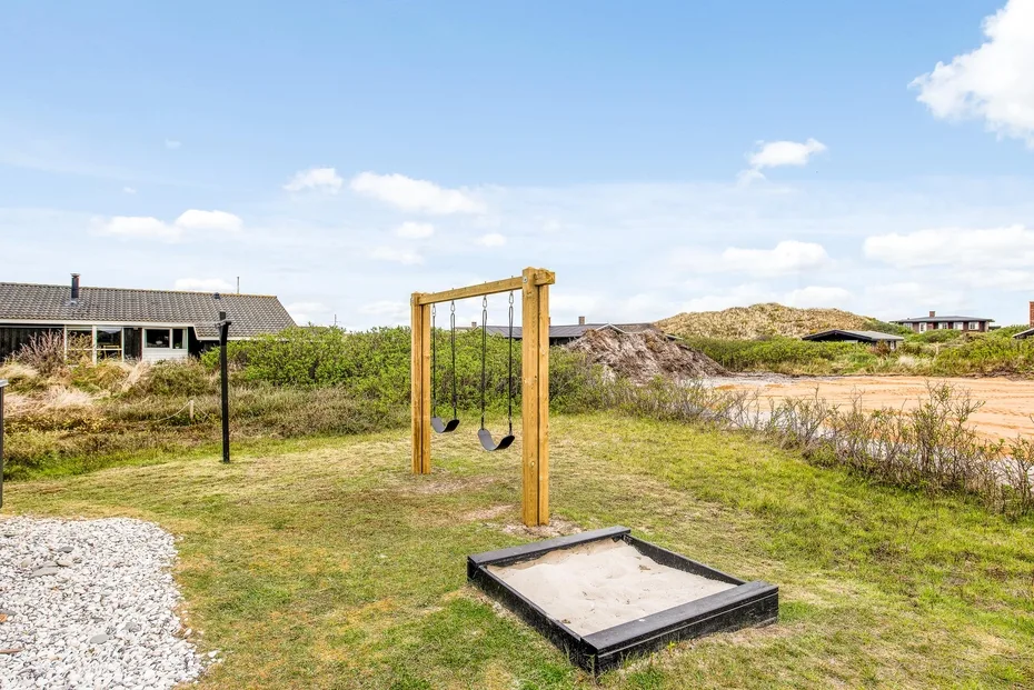 Una zona de juegos al aire libre con un columpio de madera y un arenero.