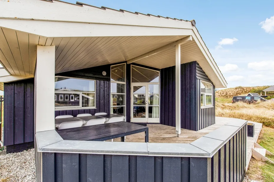Una terraza exterior cubierta con una zona de asientos junto a una casa moderna.