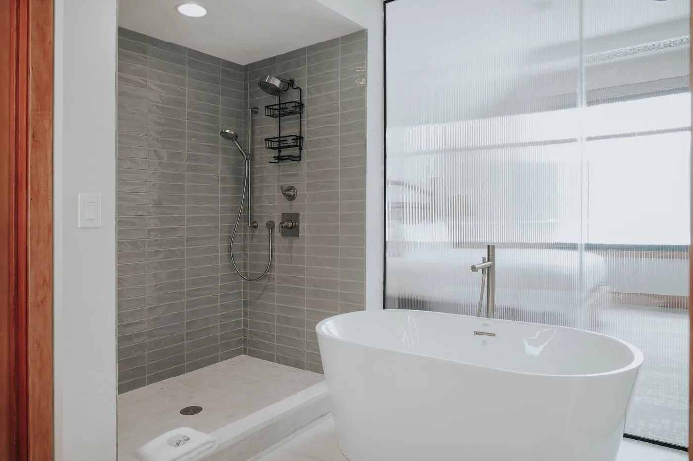 A bathroom with a freestanding bathtub beside a tiled shower.