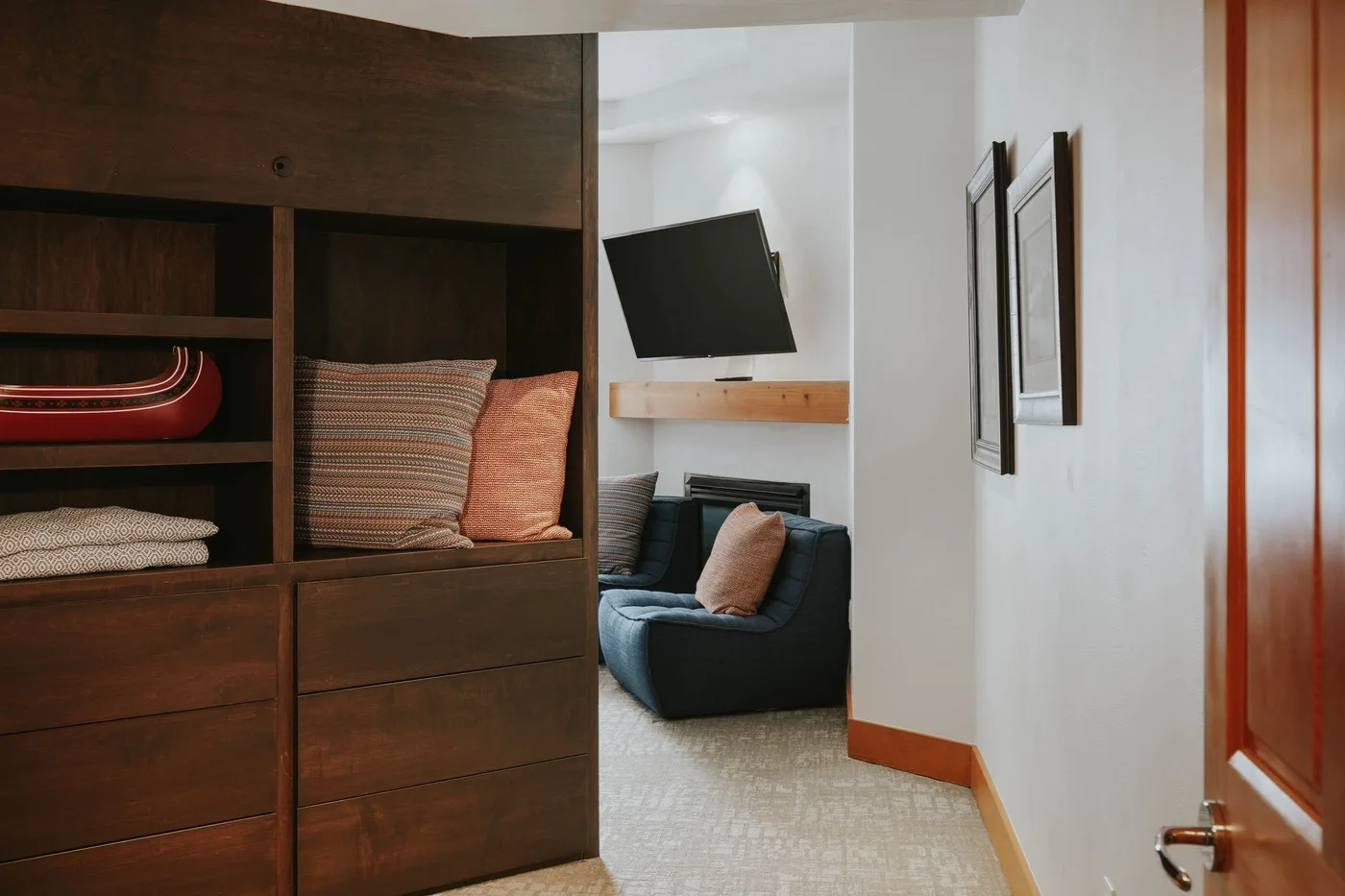 A hallway opens onto a seating area with a dark armchair and wall-mounted television.