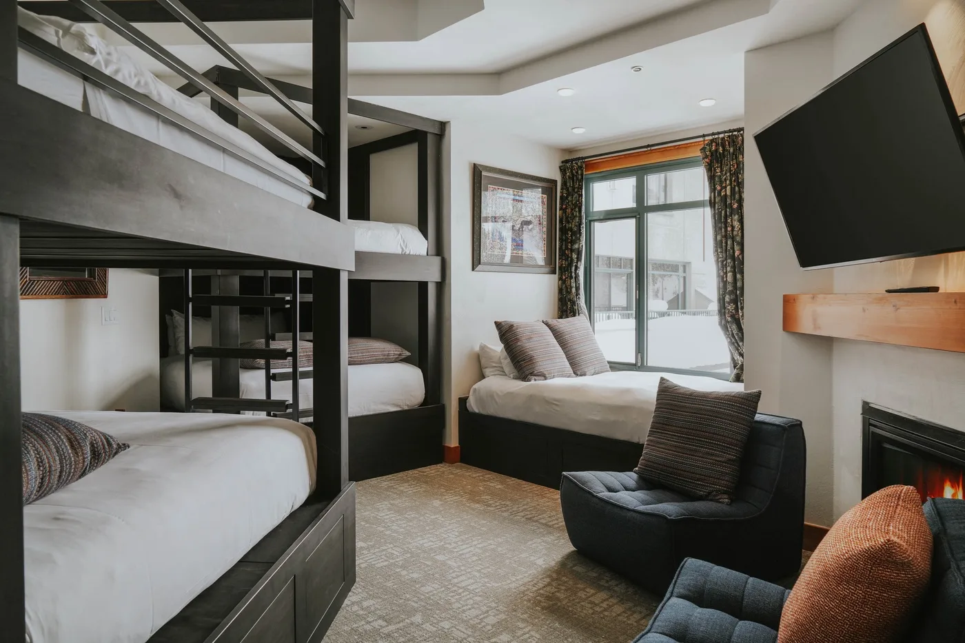 A bedroom with two bunk beds, a sitting area, and a large window.