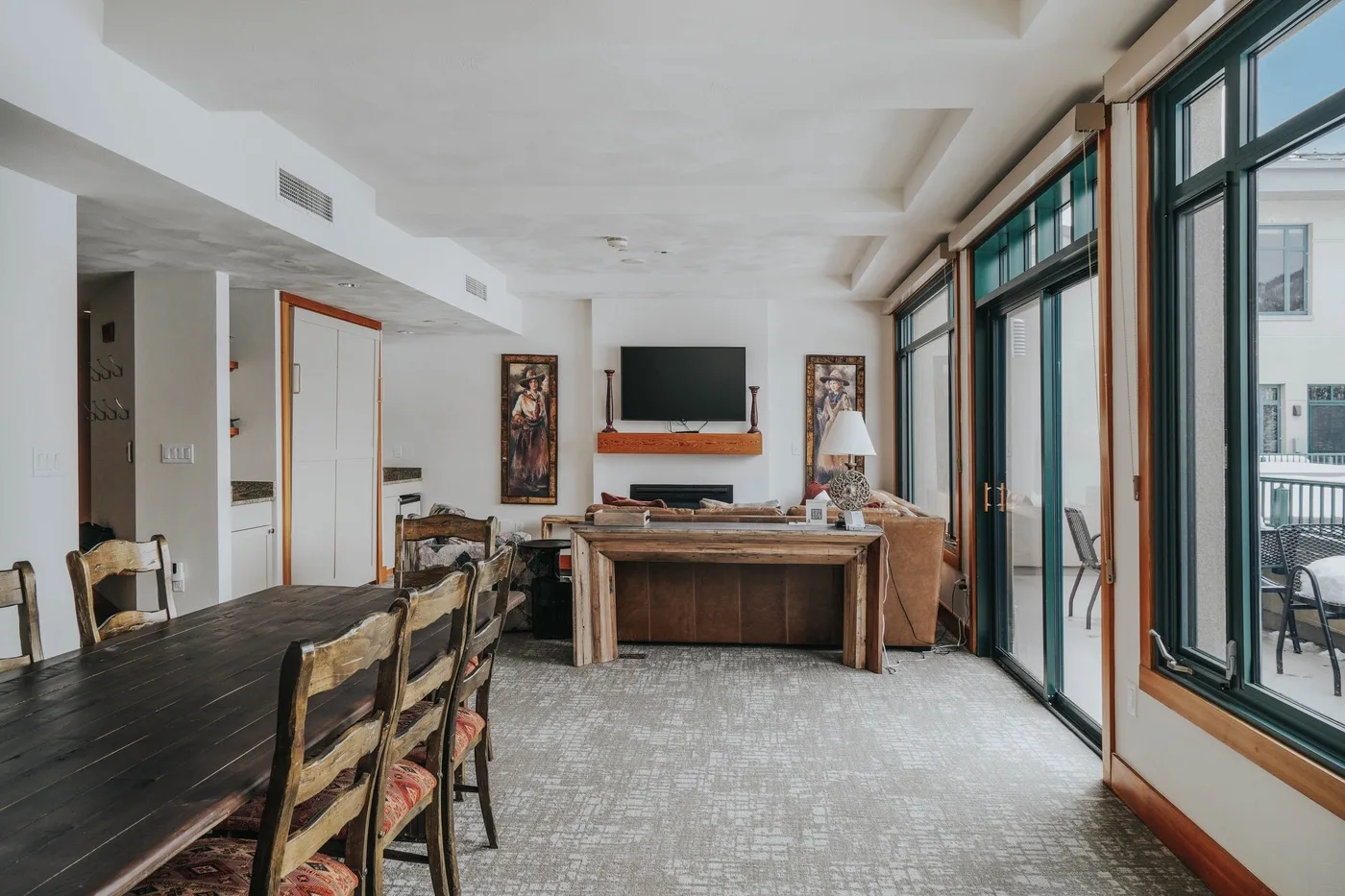 A bright living and dining area with a long table and seating beside large windows.