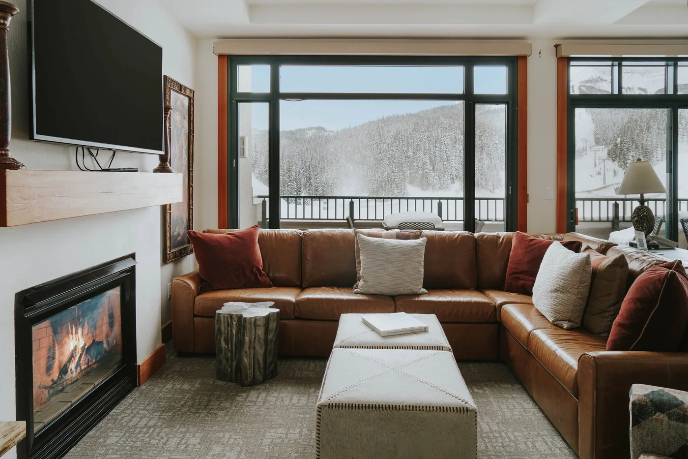 A living room with a sectional seating area facing large windows overlooking a snowy landscape.