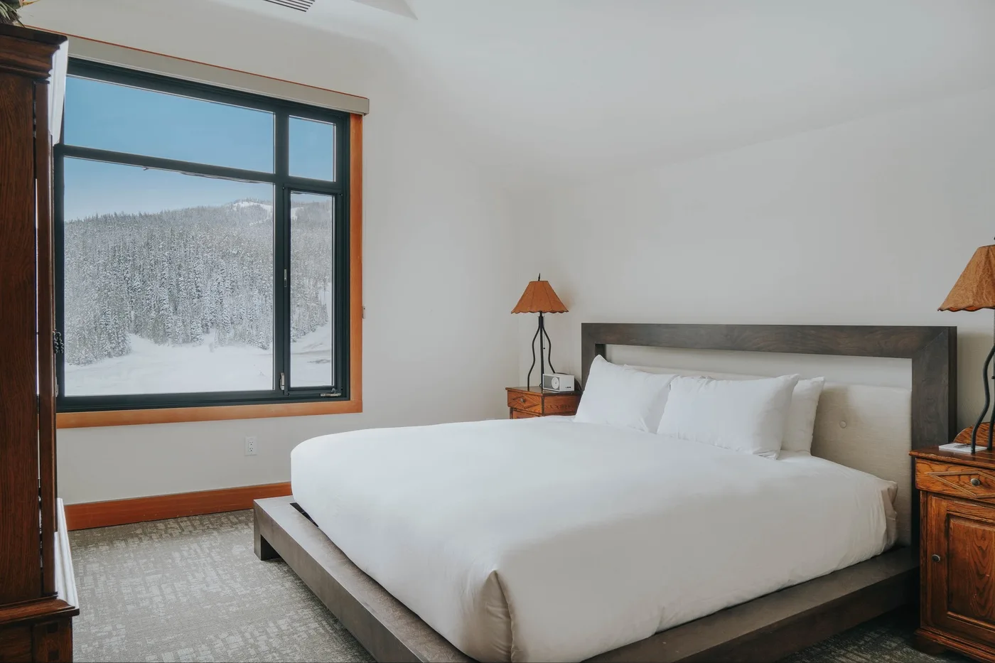 A bright bedroom with a large bed and a snowy landscape visible through the window.