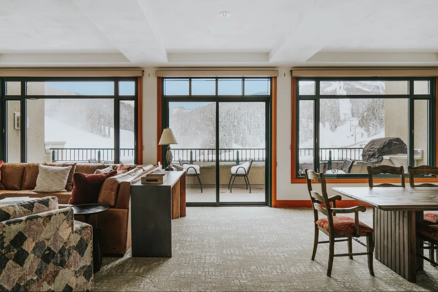 A bright living and dining area opens onto a balcony through large glass doors.
