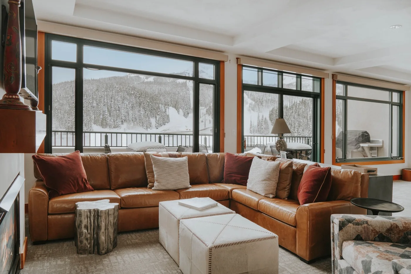 A living room with brown seating and large windows overlooking a snowy landscape.