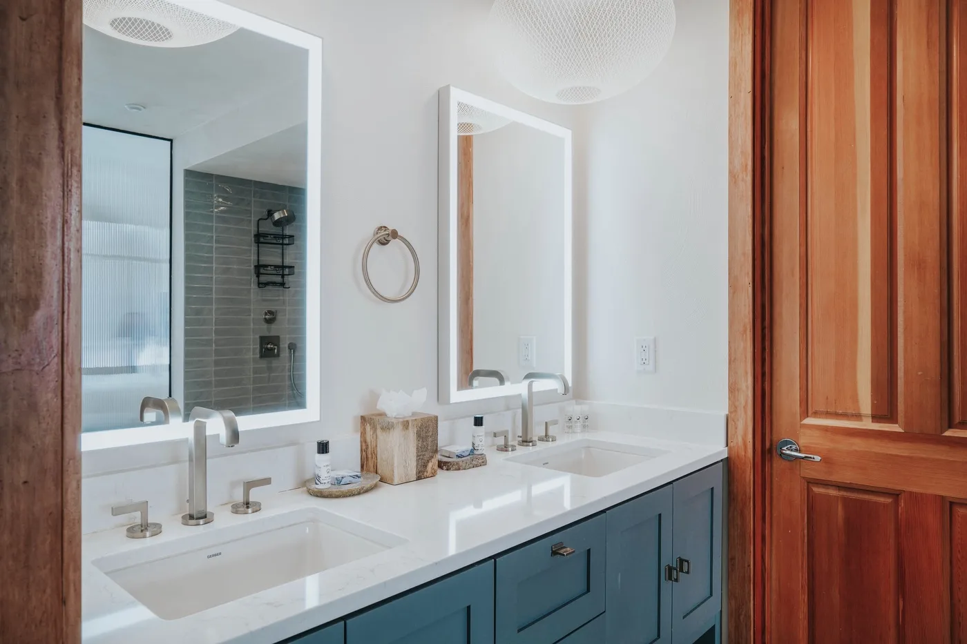A bright bathroom with a double sink vanity and wall mirrors.