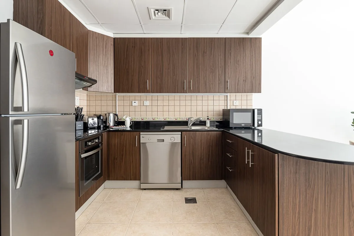 A modern kitchen with dark cabinets, stainless steel appliances, and a tiled backsplash.