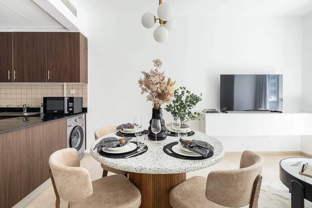 A dining area with a round table and an open kitchen behind it.
