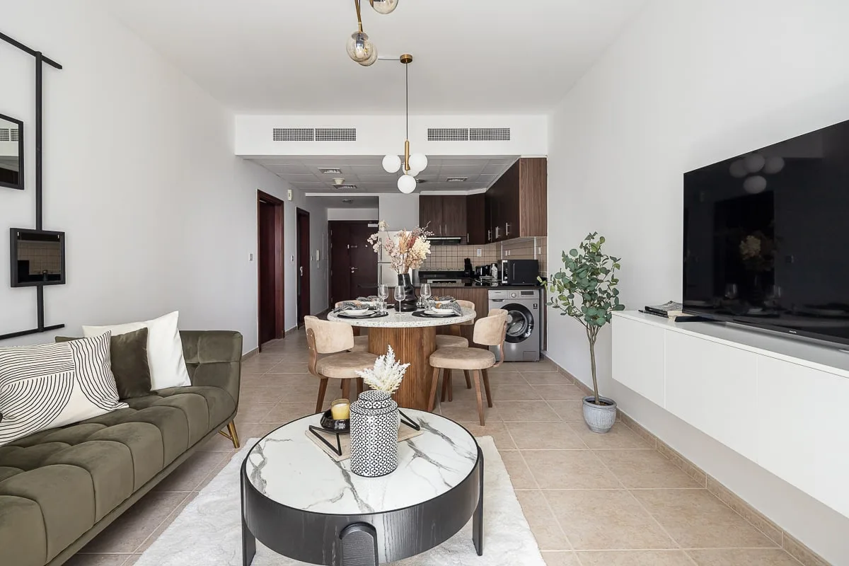 A bright living and dining area with a kitchen in the background.