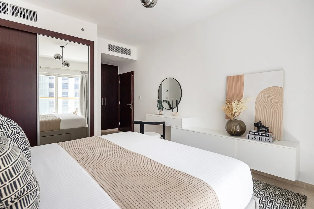 A bright bedroom with a bed and a low dresser against the wall.