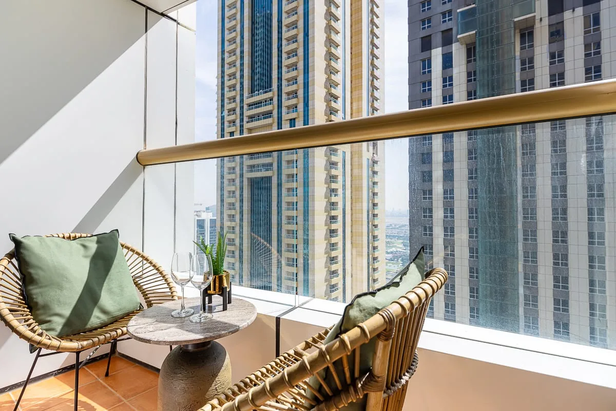 A balcony seating area with a small table and views of nearby high-rise buildings.