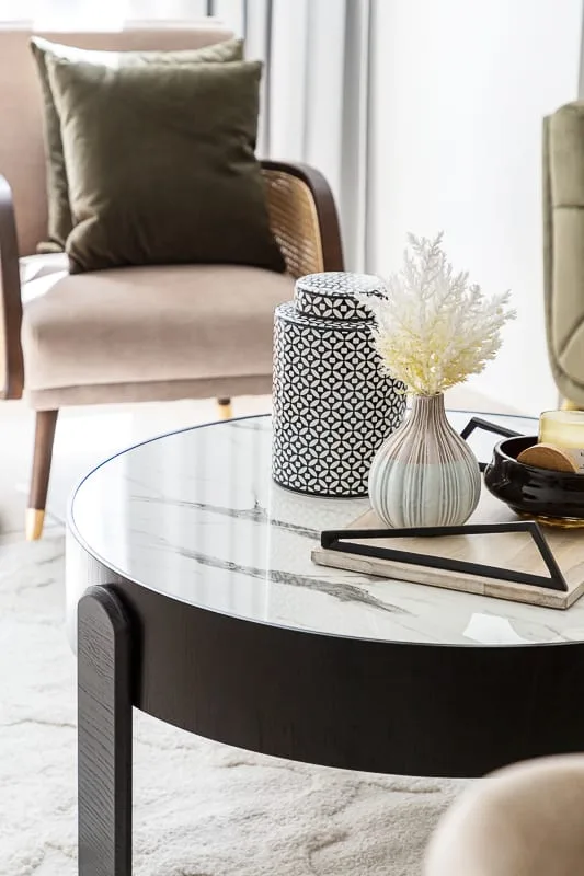 Una zona de estar presenta una mesa de centro redonda con jarrones decorativos.