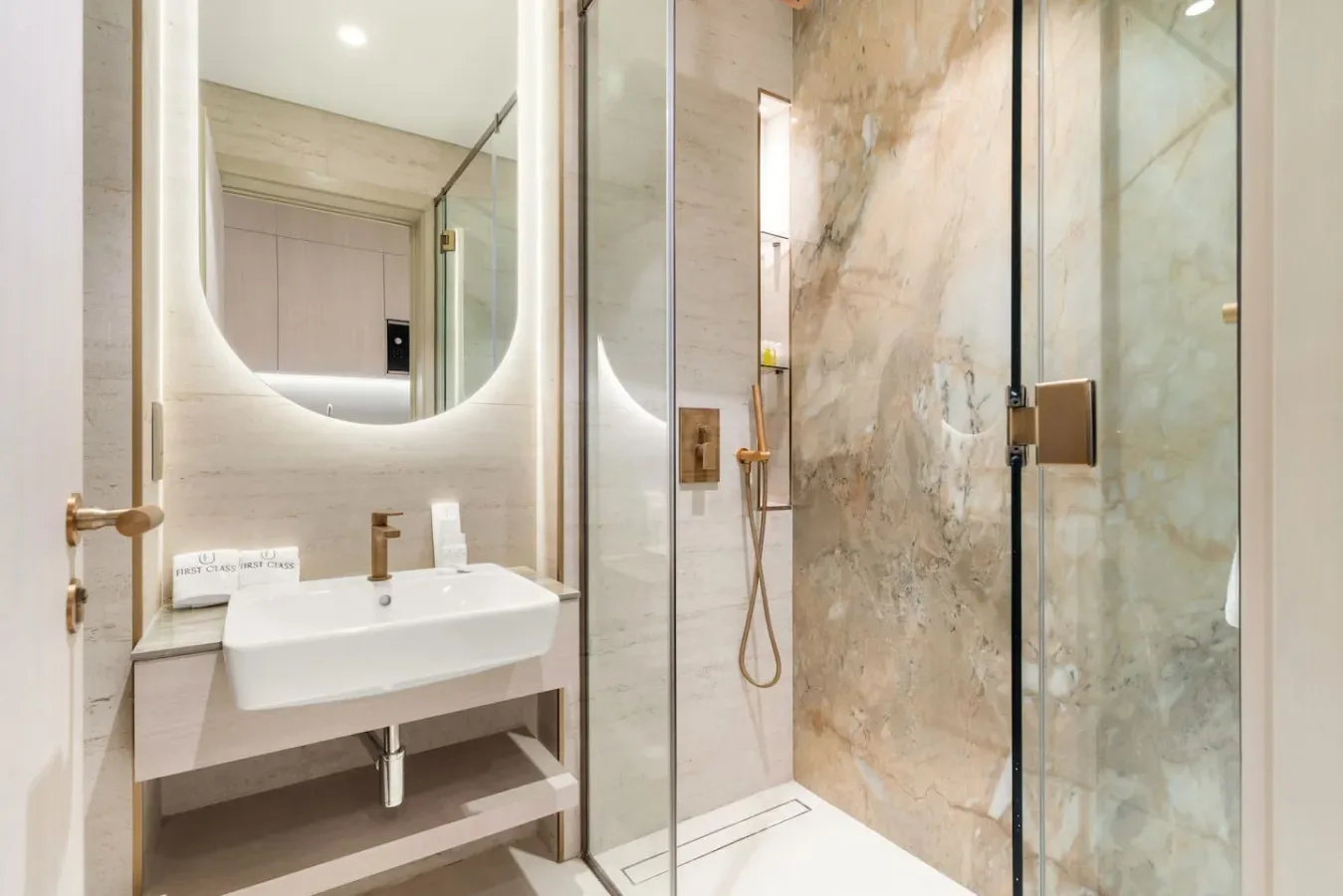 A modern bathroom with a wall-mounted sink and glass shower.