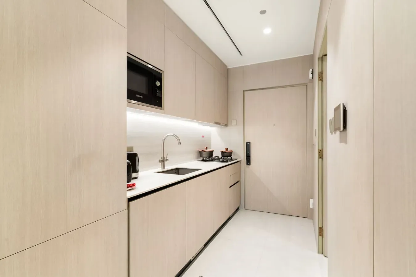 A compact kitchen with pale cabinetry, a countertop, and a closed door.