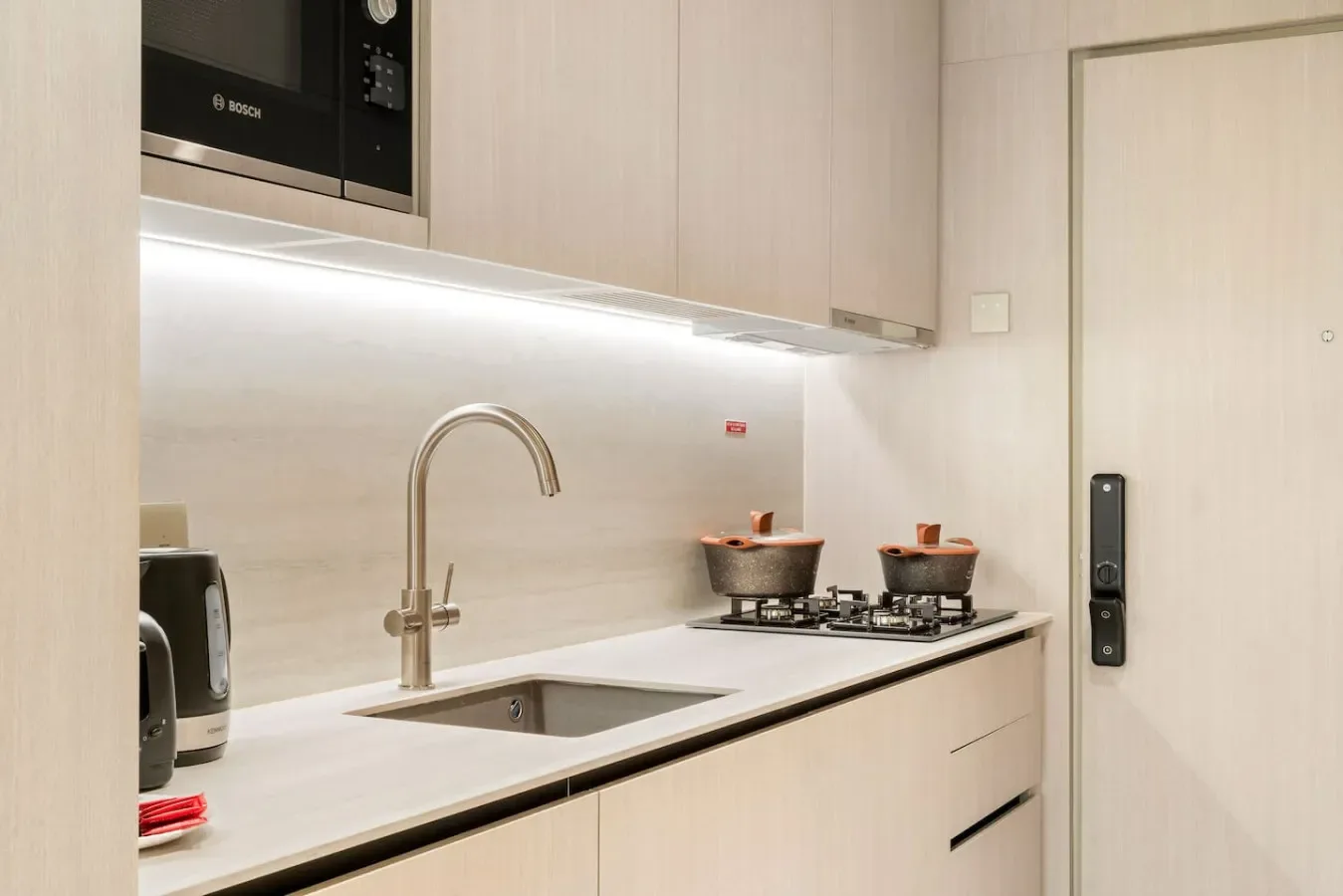 A modern kitchen with a sink, cooktop, and light-colored cabinetry.