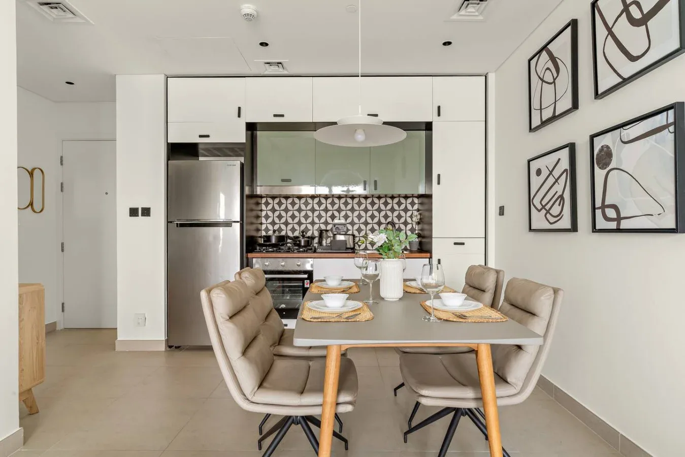 A dining area with a table set in front of a modern kitchen.