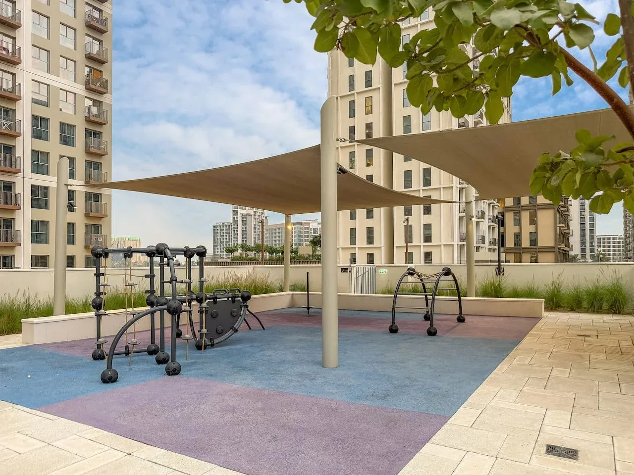 An outdoor fitness area with exercise equipment beneath shade canopies.