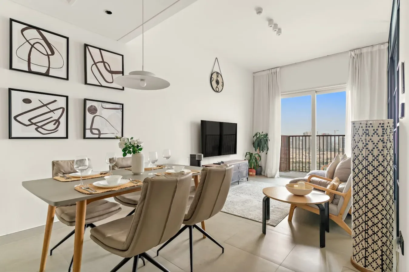 Una luminosa sala de estar y comedor con mesa, asientos y ventanales.
