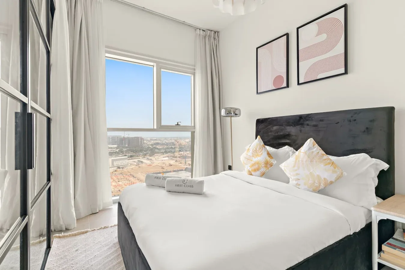 A bright bedroom with a neatly made bed beside a large window.