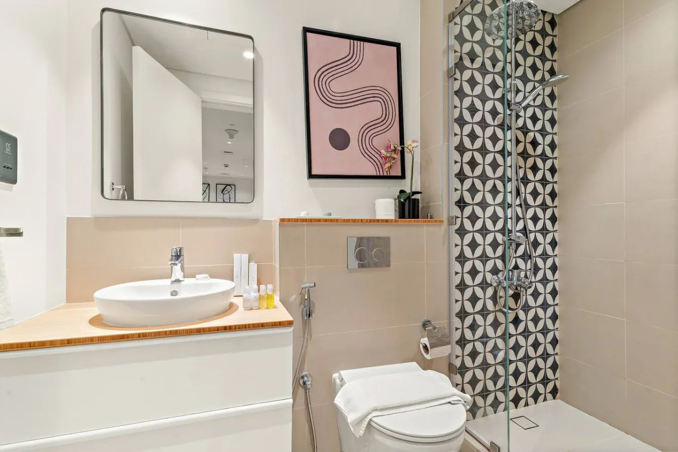 A modern bathroom with a sink, toilet, and patterned shower wall.
