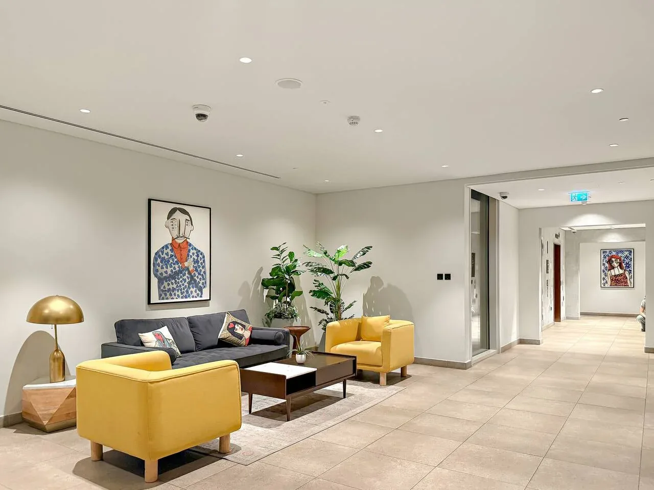 A lounge with yellow seating, a dark sofa, and potted plants.