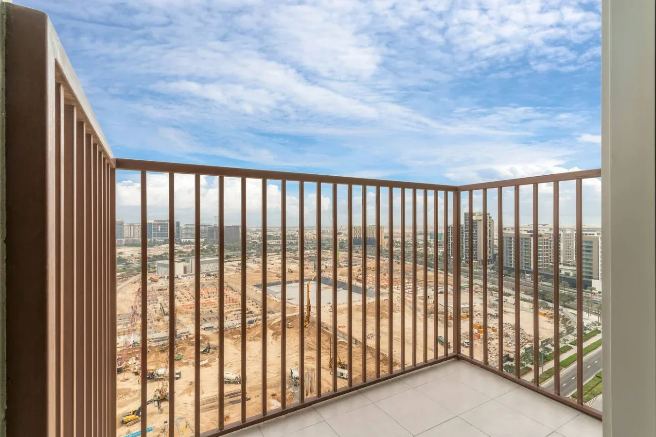 A balcony overlooks a cityscape beneath a partly cloudy sky.