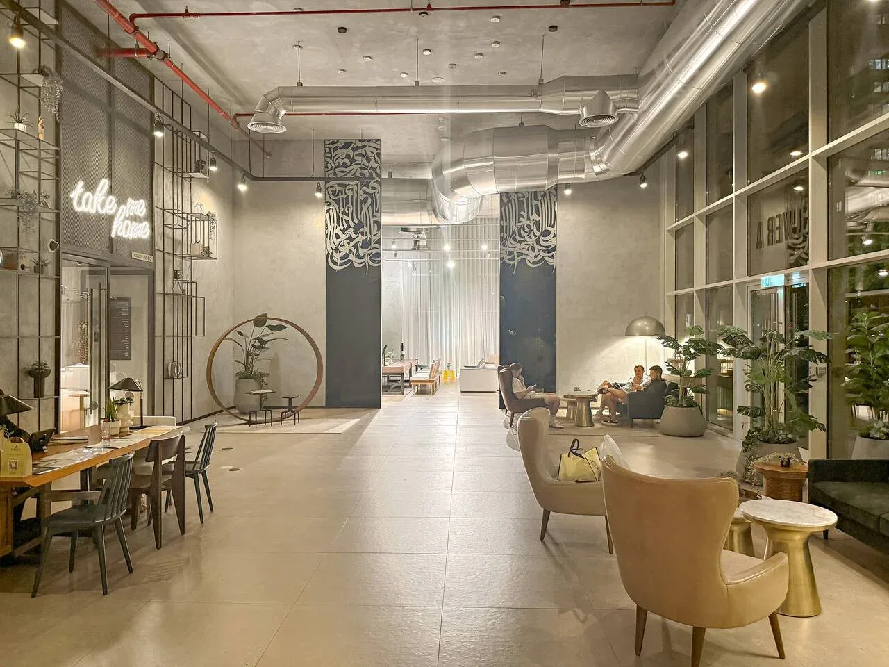 A modern lounge with seating, tables, and tall windows.