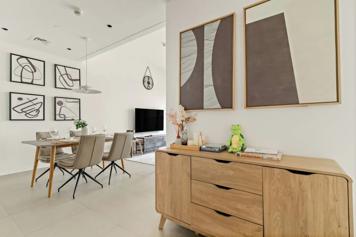 A bright dining and living area with a table, seating, and framed artwork.